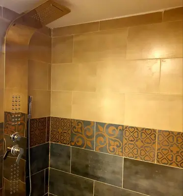 a bathroom with a shower with a tile wall at Captains Desert Camp in Wadi Rum