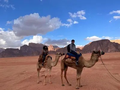 a man and a woman riding on camels in the desert at Wadi Rum Desert Camp in Wadi Rum