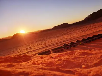a group of chairs sitting in the desert at sunset at Wadi Rum Desert Camp in Wadi Rum
