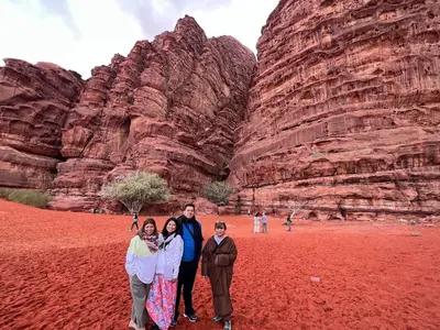 a group of people standing in front of a rock formation at Wadi Rum Desert Camp in Wadi Rum