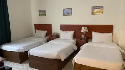 a bedroom with two beds with white sheets and a lamp at New Park Hotel in Amman