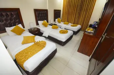 a hotel room with three beds with yellow pillows at Sharah Mountains Hotel in Wadi Musa