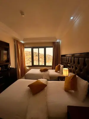 a hotel room with two beds and a window at Sharah Mountains Hotel in Wadi Musa
