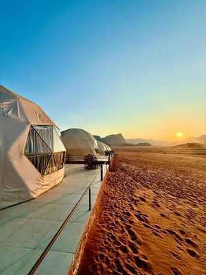 a row of tents on the beach at sunset at Beauty Wadi Rum Luxury Camp in Wadi Rum