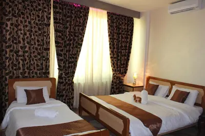 two beds in a hotel room with a teddy bear sitting on them at Arab Tower Hotel in Amman