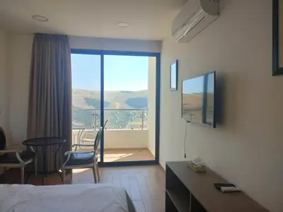 a hotel room with a bed and a view of a balcony at Sindyan Resort in Amman