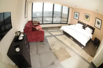 a bedroom with a bed and a couch and a tv at Sindyan Resort in Amman