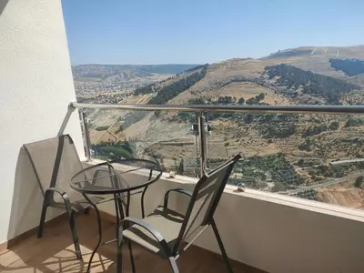 a table and chairs on a balcony with a view at Sindyan Resort in Amman