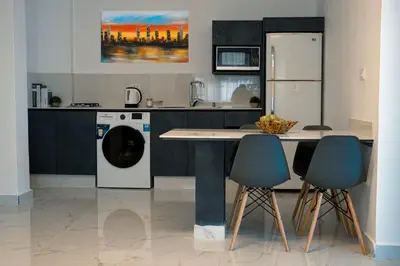 a kitchen with a refrigerator and a table and chairs at Al Kawther Hotel Apartments in Amman