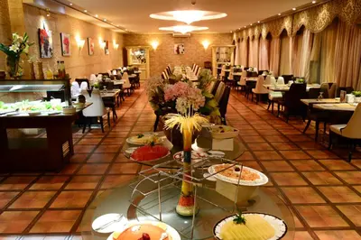 a restaurant with tables and chairs and food on display at Larsa Hotel in Amman
