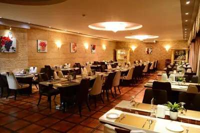 a dining room filled with tables and chairs at Larsa Hotel in Amman