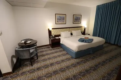 a hotel room with a large bed and a desk at Larsa Hotel in Amman