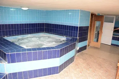 a blue tiled bathroom with a hot tub at Rojina Hotel in Amman