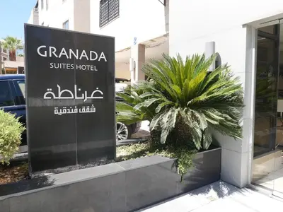 a sign in front of a building with a palm tree at Granada Suites Hotel in Amman