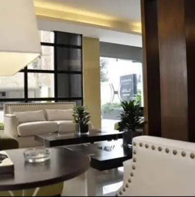 a living room with a couch and a table and chairs at Granada Suites Hotel in Amman