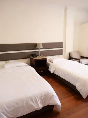 a bedroom with two beds and a table with a lamp at Granada Suites Hotel in Amman