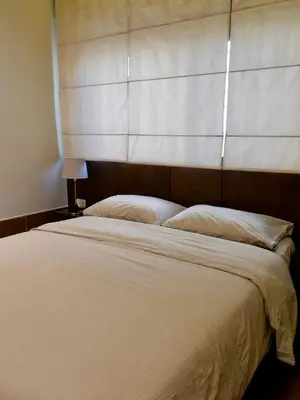 a bedroom with a large white bed with a headboard at Granada Suites Hotel in Amman