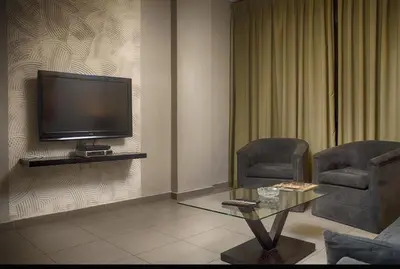 a living room with two chairs and a flat screen tv at Crystal Suites in Amman