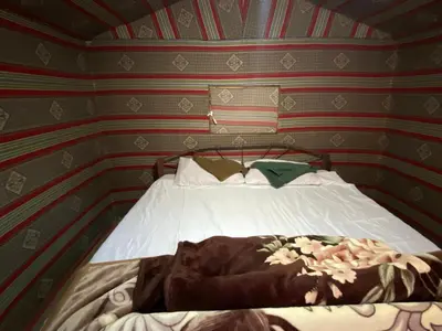 a bedroom with a bed in a room with striped walls at Wadi Rum Jordan Camp in Wadi Rum
