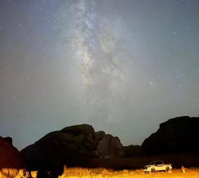 a car parked in the desert under a starry sky at Wadi Rum Jordan Camp in Wadi Rum