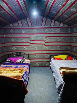 a bedroom with two beds in a room with striped walls at Wadi Rum Jordan Camp in Wadi Rum
