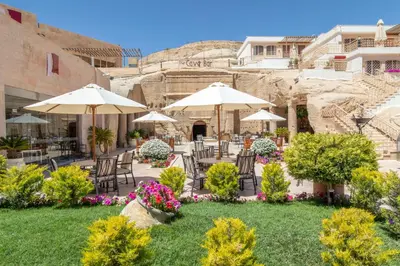 a patio with tables and umbrellas and flowers at Petra Guest House Hotel in Petra