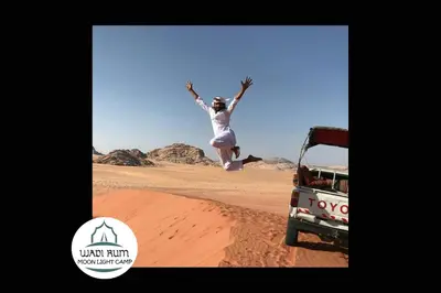 a woman jumping in the air in the desert at Wadi Rum Moon Light Camp in Wadi Rum