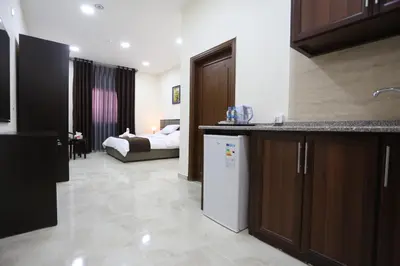 a kitchen with a refrigerator and a room with a bed at 7Boys Hotel in Amman