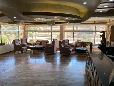 a waiting room with chairs and tables and windows at Sunset Hotel in Wadi Musa