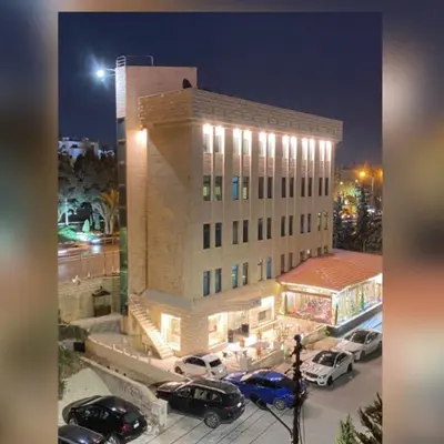 a large building with cars parked in a parking lot at Rozana Hotel in Amman