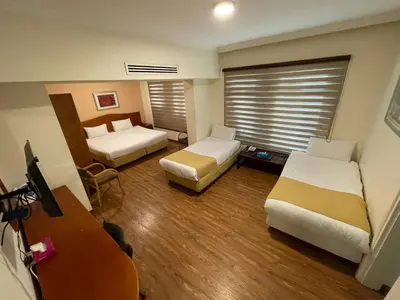 a hotel room with two beds and a television at Rozana Hotel in Amman