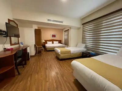 a hotel room with two beds and a desk at Rozana Hotel in Amman