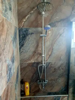 a shower in a bathroom with a stone wall at The Little B&B on the Hill in Wadi Musa