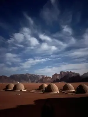 a group of domes in the desert with mountains in the background at Beyond Wadi Rum Camp in Wadi Rum