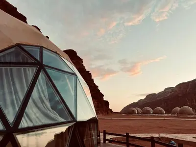 a dome house in the desert with mountains in the background at Beyond Wadi Rum Camp in Wadi Rum