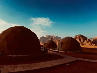 a group of tents in a desert with mountains at Beyond Wadi Rum Camp in Wadi Rum