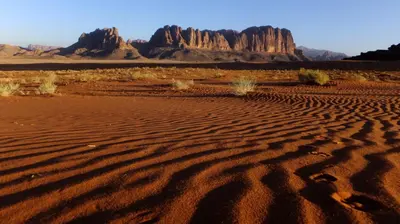 a desert with rock formations in the background at Wadi Rum Bedouin Way Camp in Wadi Rum