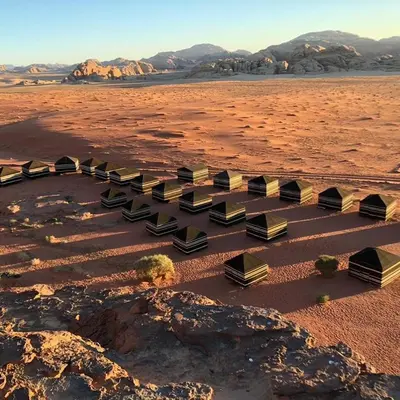 a group of benches in a desert with mountains at Wadi Rum Bedouin Way Camp in Wadi Rum