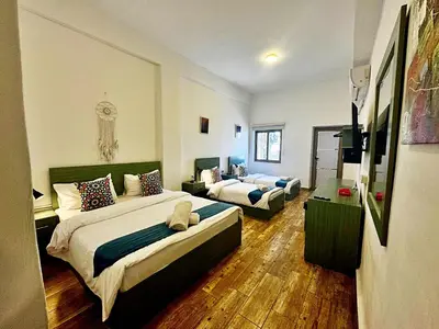 a bedroom with two beds and a living room at The Sydney Hotel in Amman