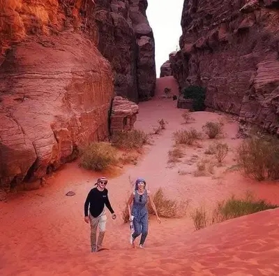 a man and a woman walking through a canyon at Yazan Desert Camp in Wadi Rum