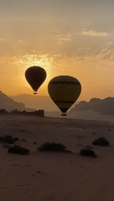 two hot air balloons flying over the desert at sunset at Yazan Desert Camp in Wadi Rum