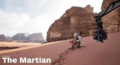 a man is kneeling in the desert near a tent at Yazan Desert Camp in Wadi Rum