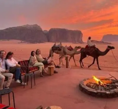 a group of people sitting around a fire in the desert at Yazan Desert Camp in Wadi Rum
