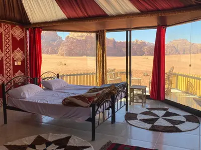a bedroom with a bed and a large window at Bedouin Tours Camp in Wadi Rum