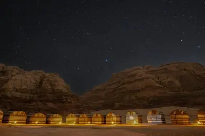 a starry night with a row of huts in the desert at Bedouin Tours Camp in Wadi Rum