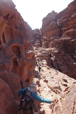 a group of people hiking through a canyon at Wadi Rum Fire Camp in Wadi Rum