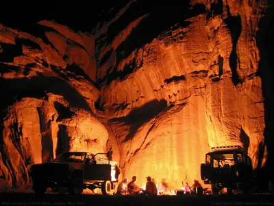 two cars parked in front of a cave at Wadi Rum Fire Camp in Wadi Rum