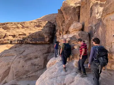 a group of people walking on rocks in a canyon at Wadi Rum Fire Camp in Wadi Rum