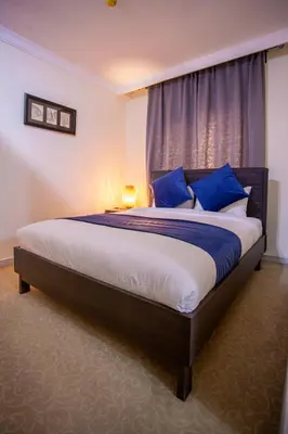 a bedroom with a large bed with blue pillows at Al Basem Hotel in Amman