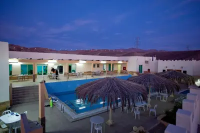 a resort with a swimming pool with umbrellas and tables at Red Sea Dive Center in Aqaba